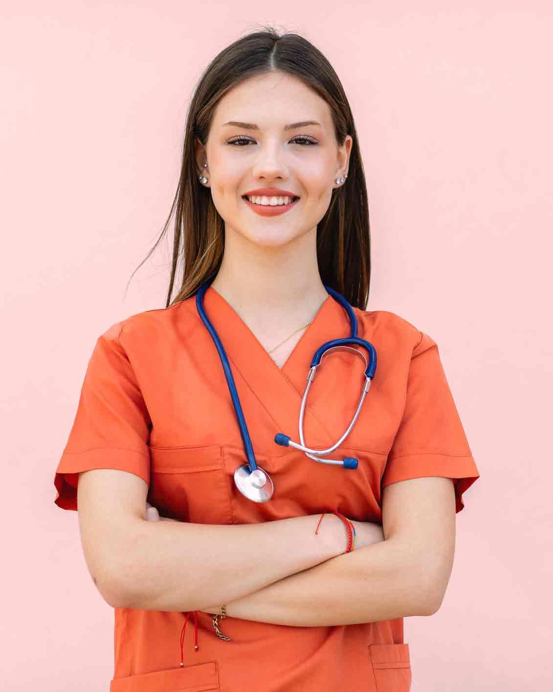 A nurse with a stethoscope around her neck is smiling with her arms crossed.