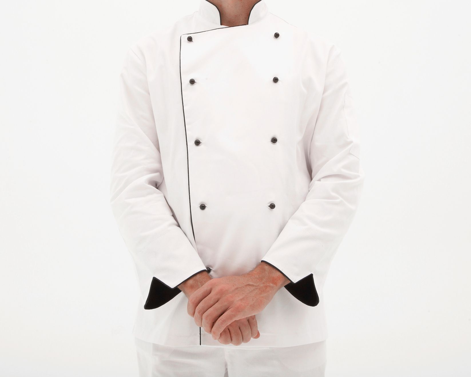 A man in a white chef 's jacket is standing with his hands folded