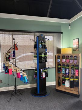 Retail display with hanging fishing rods, a black rotating rack, and a rack of packaged items in a store.