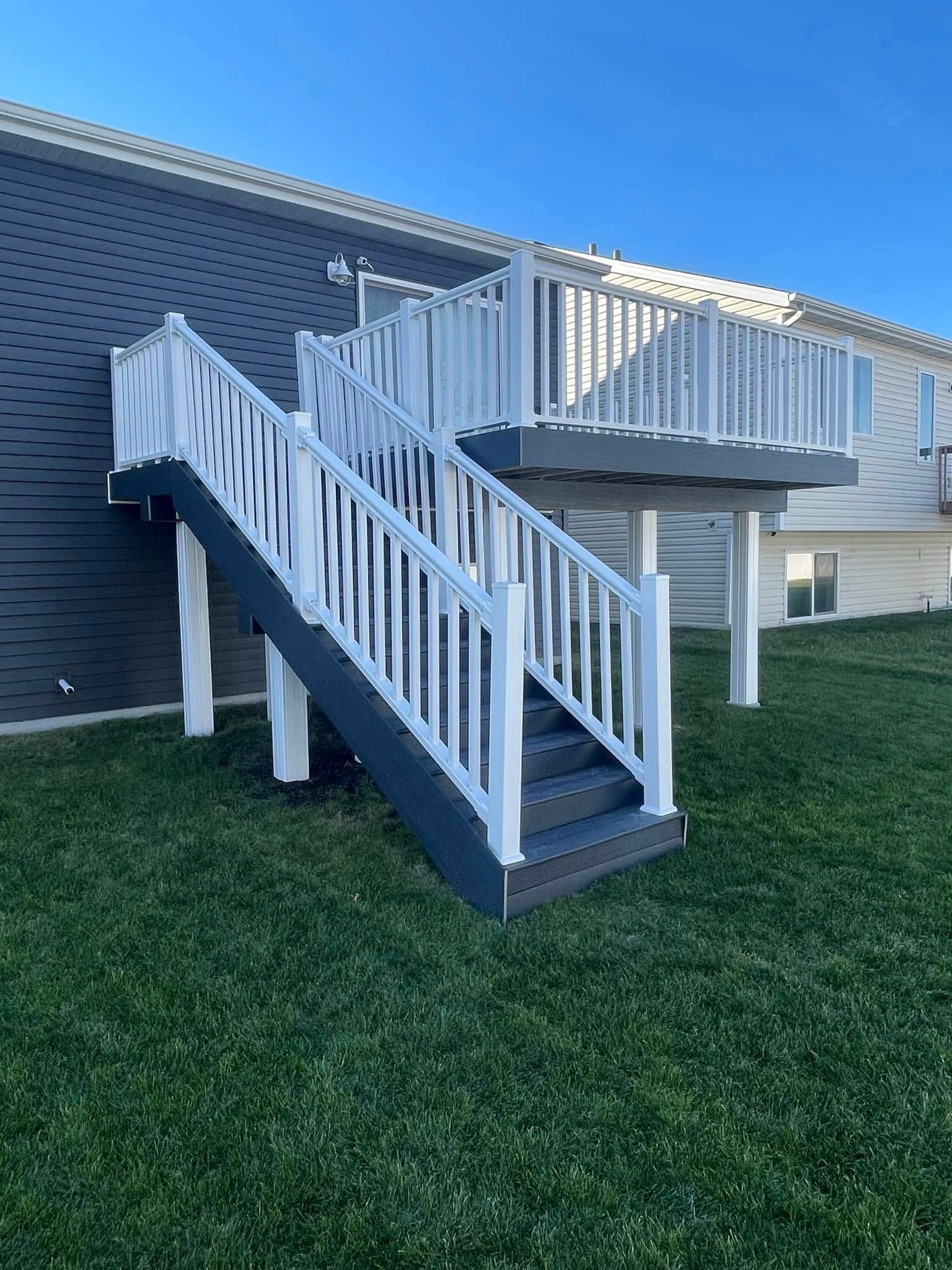 A deck with stairs leading up to it and a house in the background.