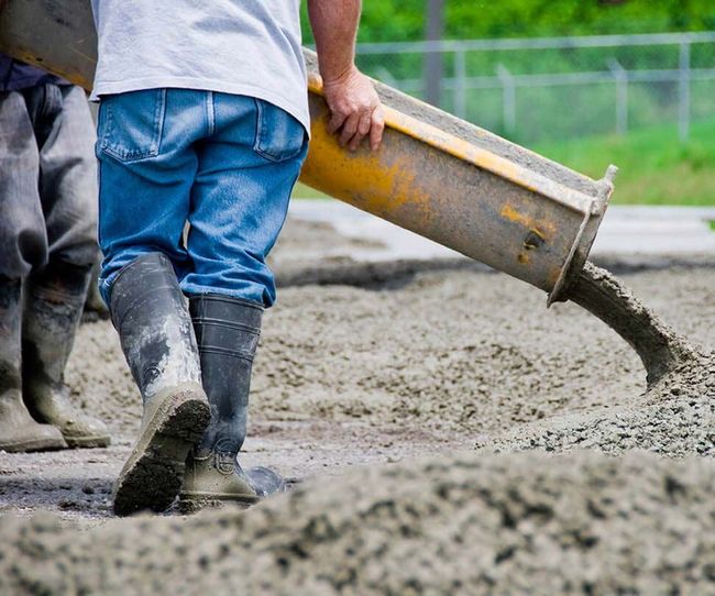 A man is pouring concrete from a pump on a construction site in Clifton, IL.
