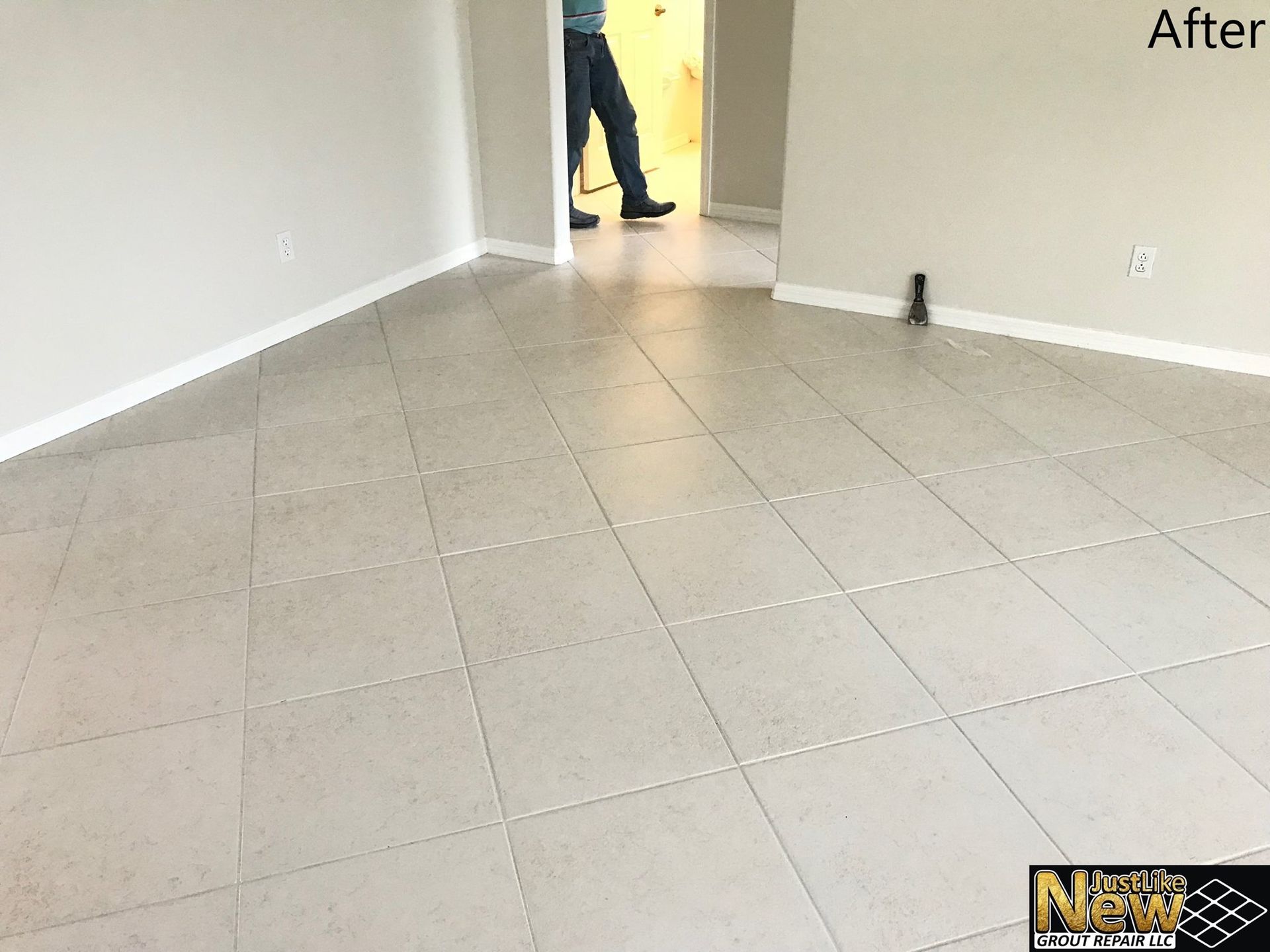 A room with a tiled floor and a person standing in the doorway.