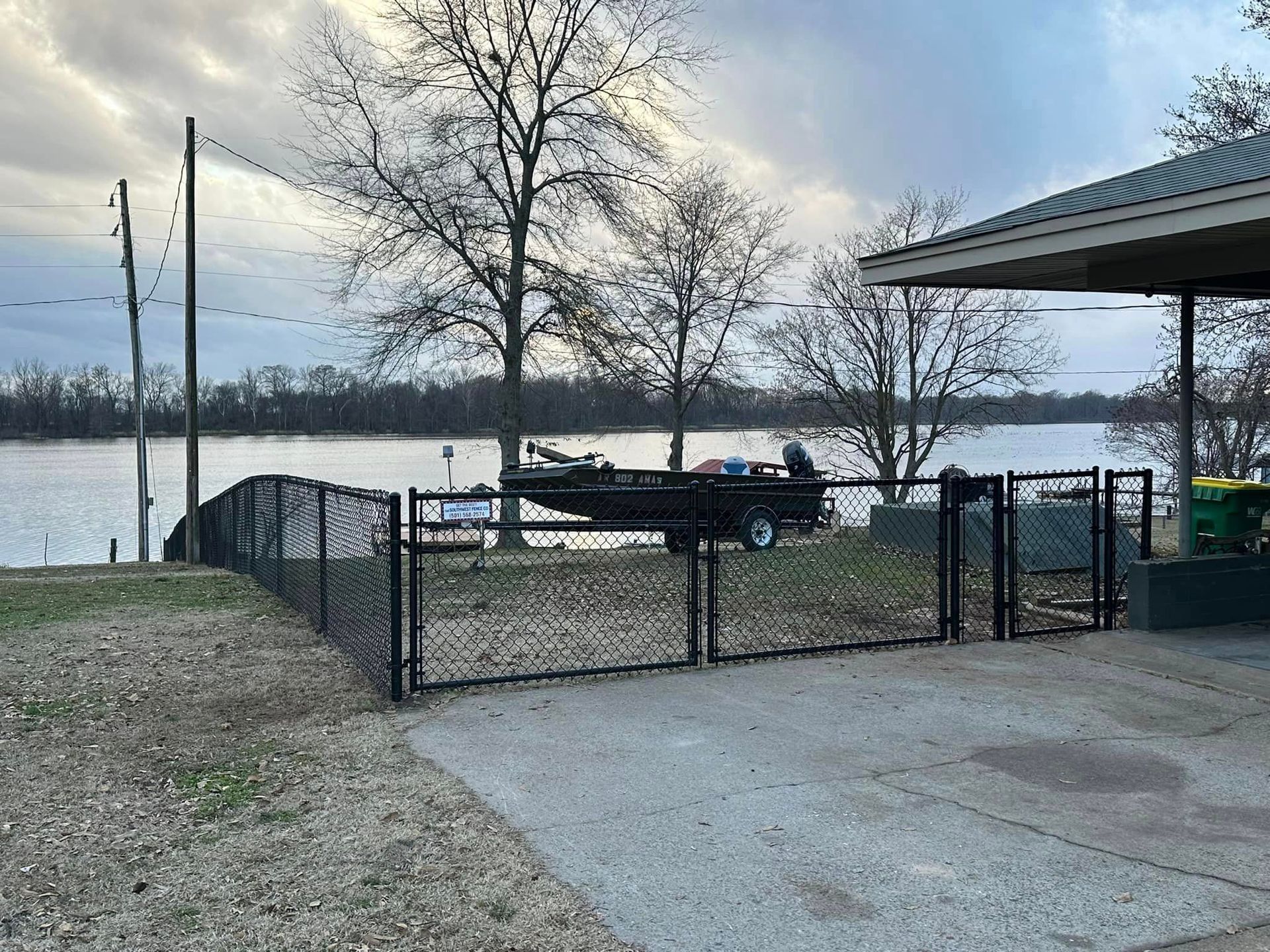 A boat is parked in front of a fence next to a lake.
