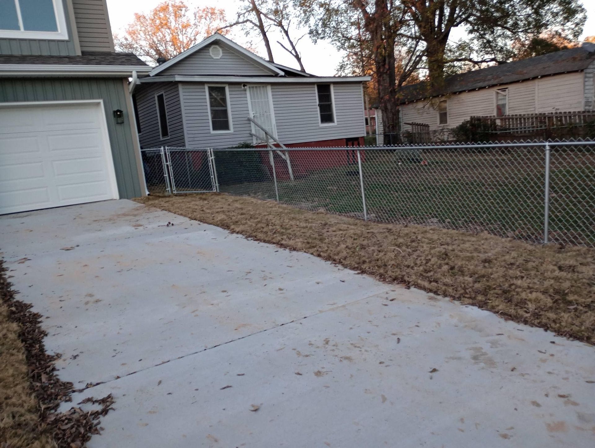 A chain link fence is surrounding a house and a driveway.
