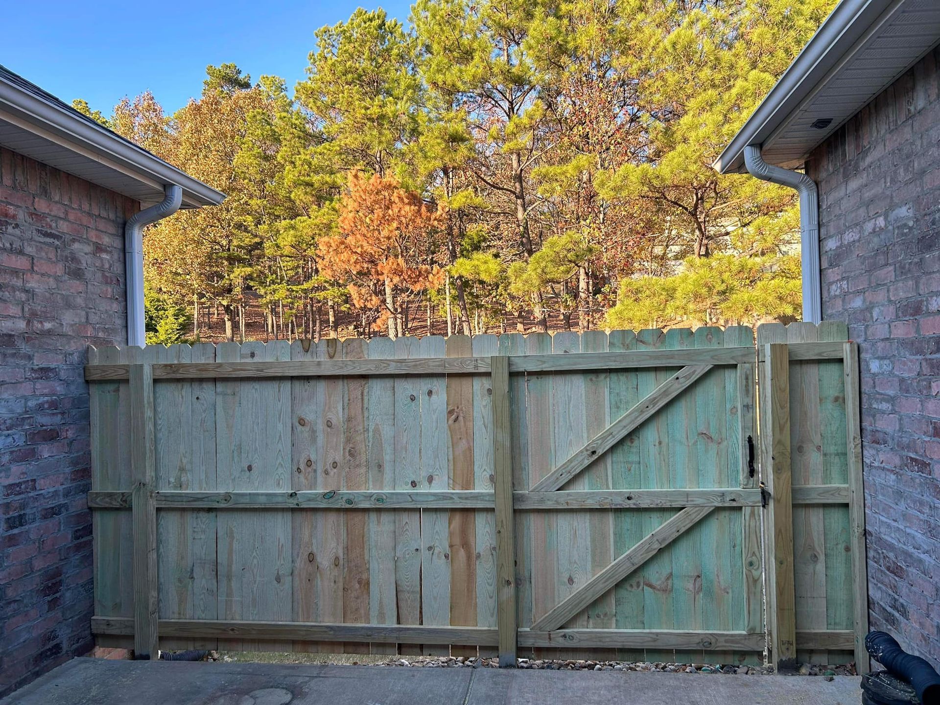 A wooden fence with a gate in front of a brick house.