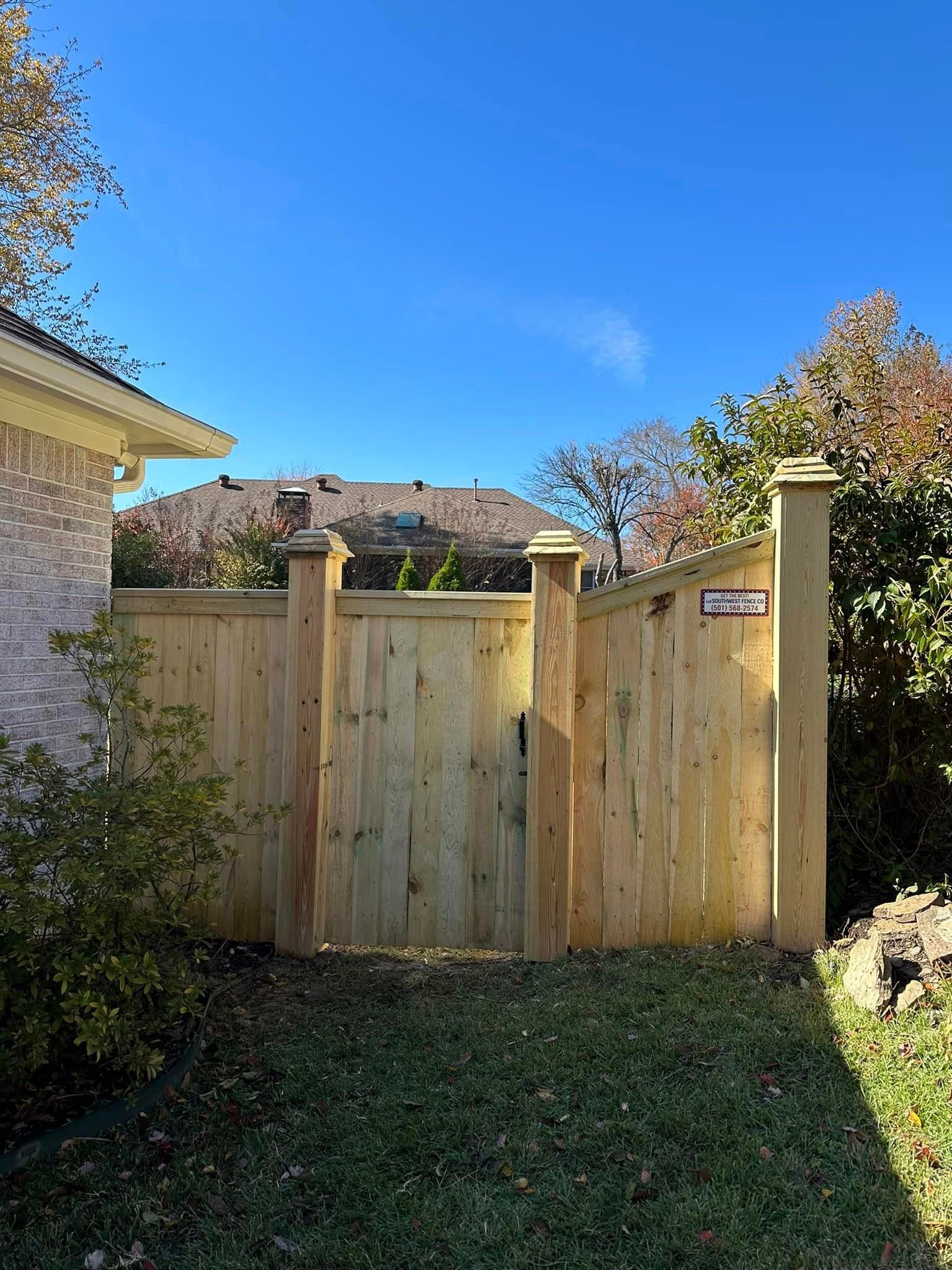 A wooden fence with a gate in the backyard of a house.