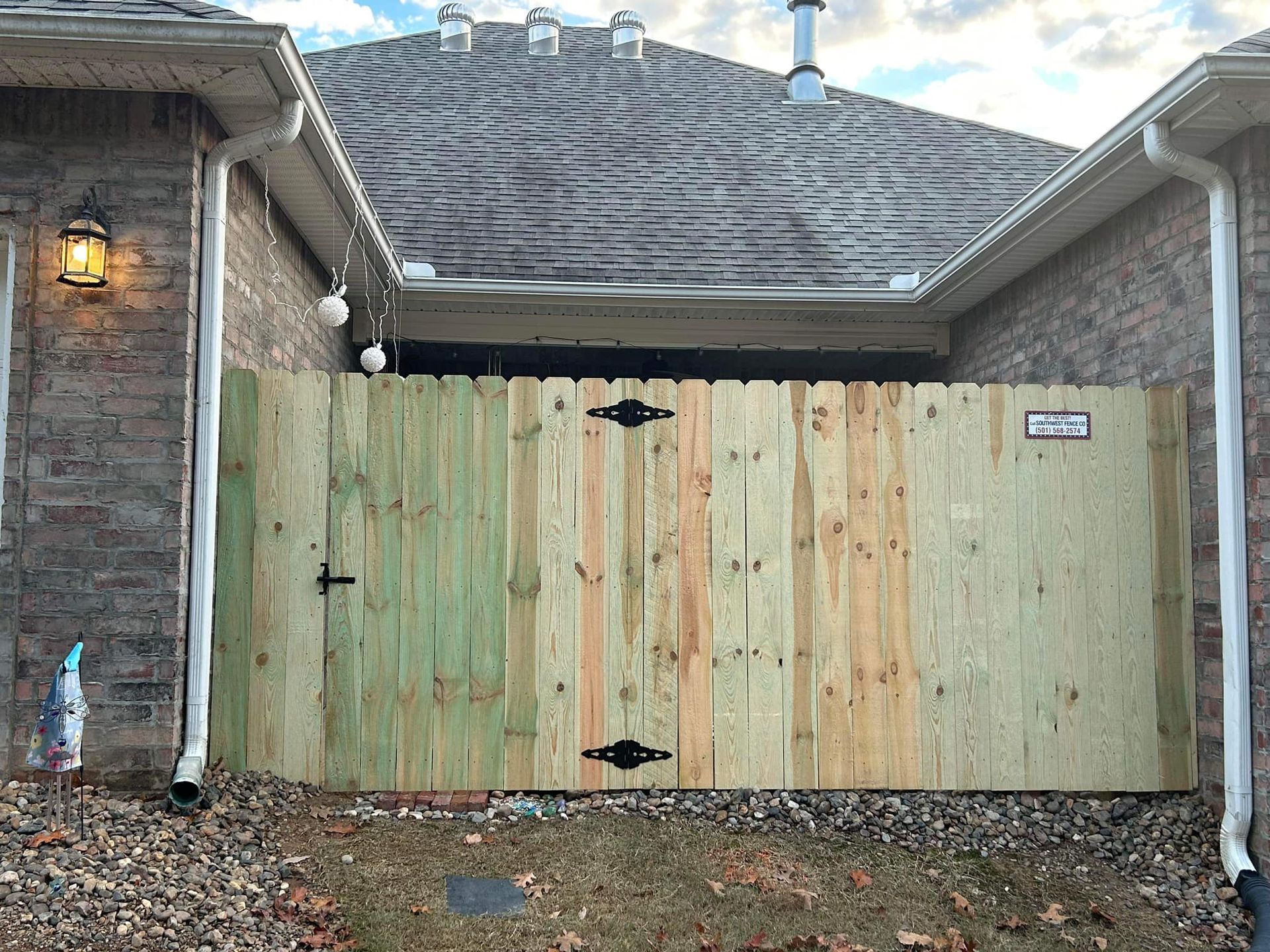 A wooden fence is sitting in front of a brick house.