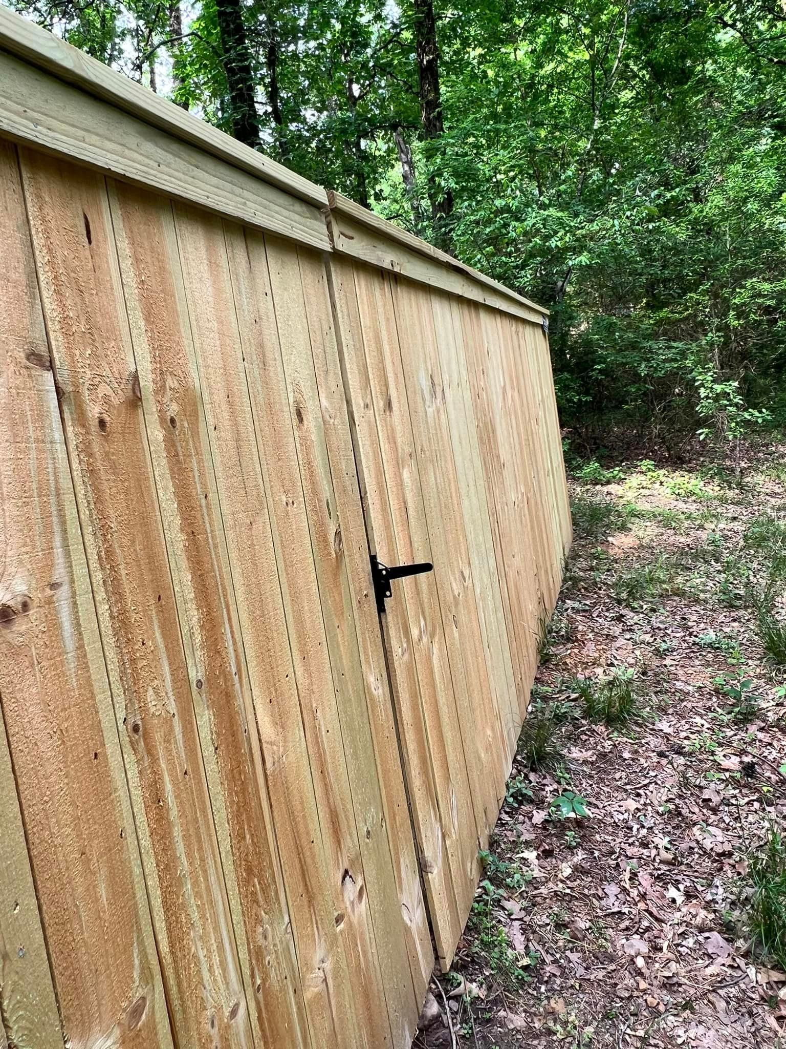 A wooden fence is sitting in the middle of a forest.