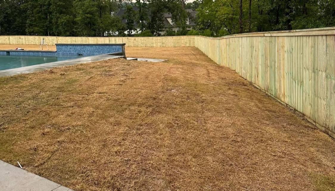 A wooden fence surrounds a swimming pool in a backyard.