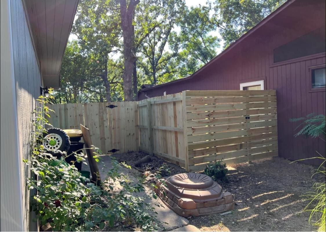 A wooden fence is in the backyard of a house.