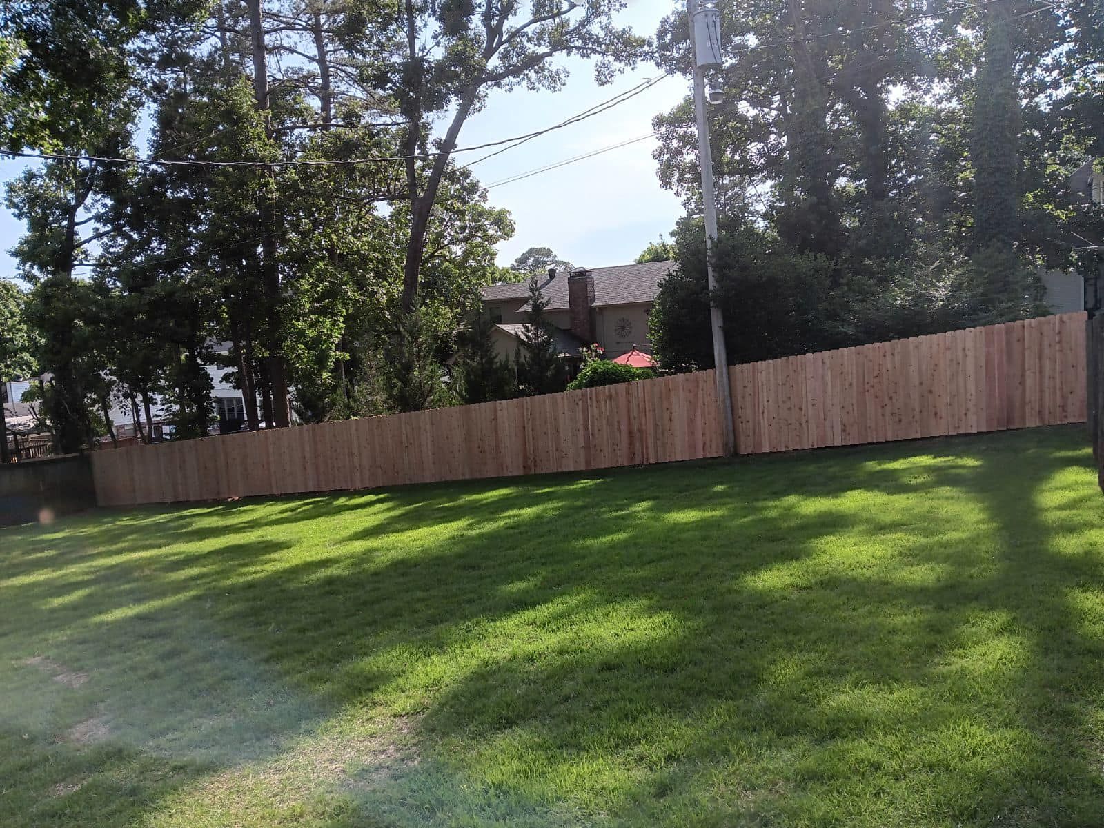 A wooden fence surrounds a lush green yard.