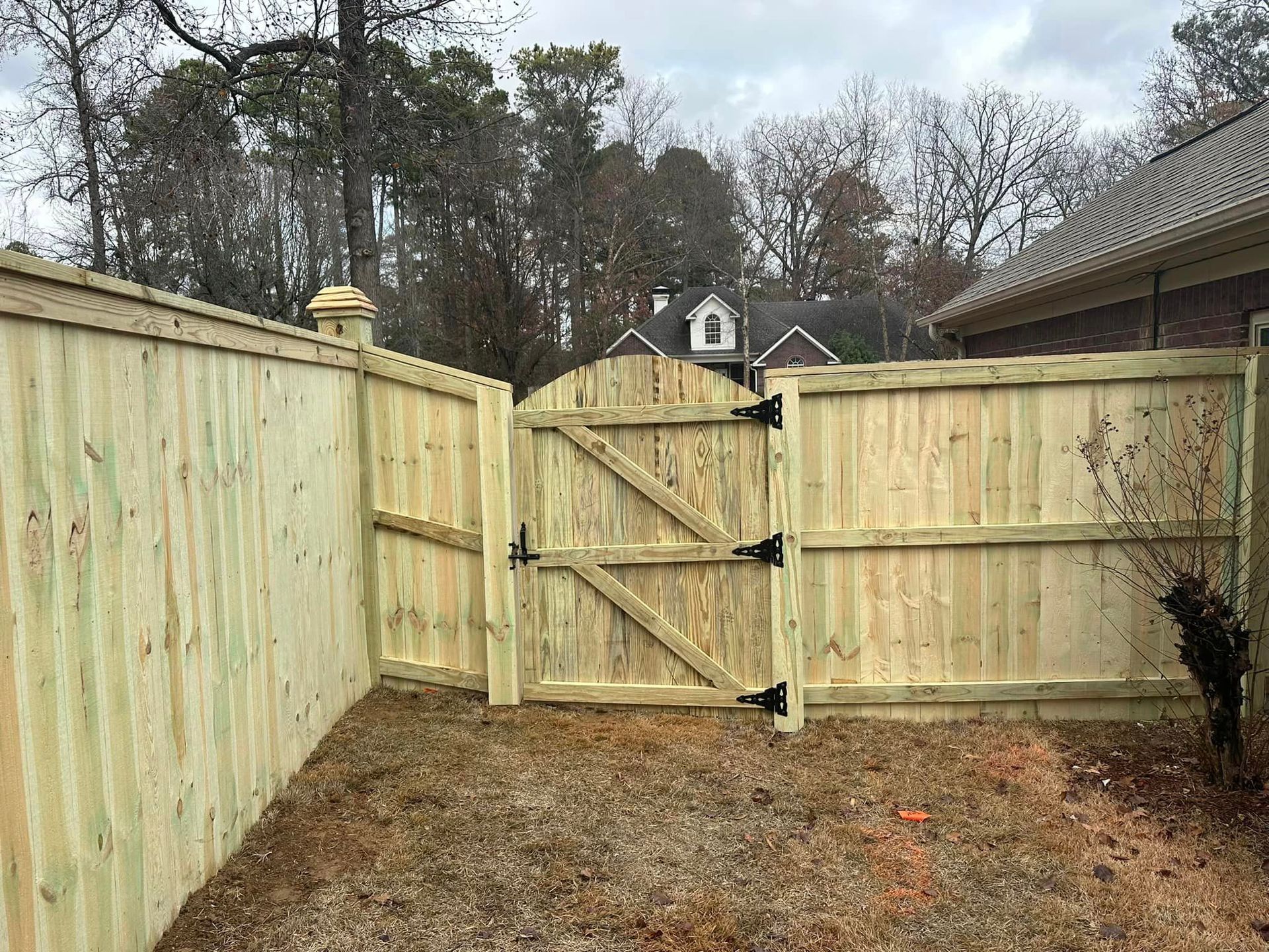 A wooden fence with a gate in the backyard of a house.
