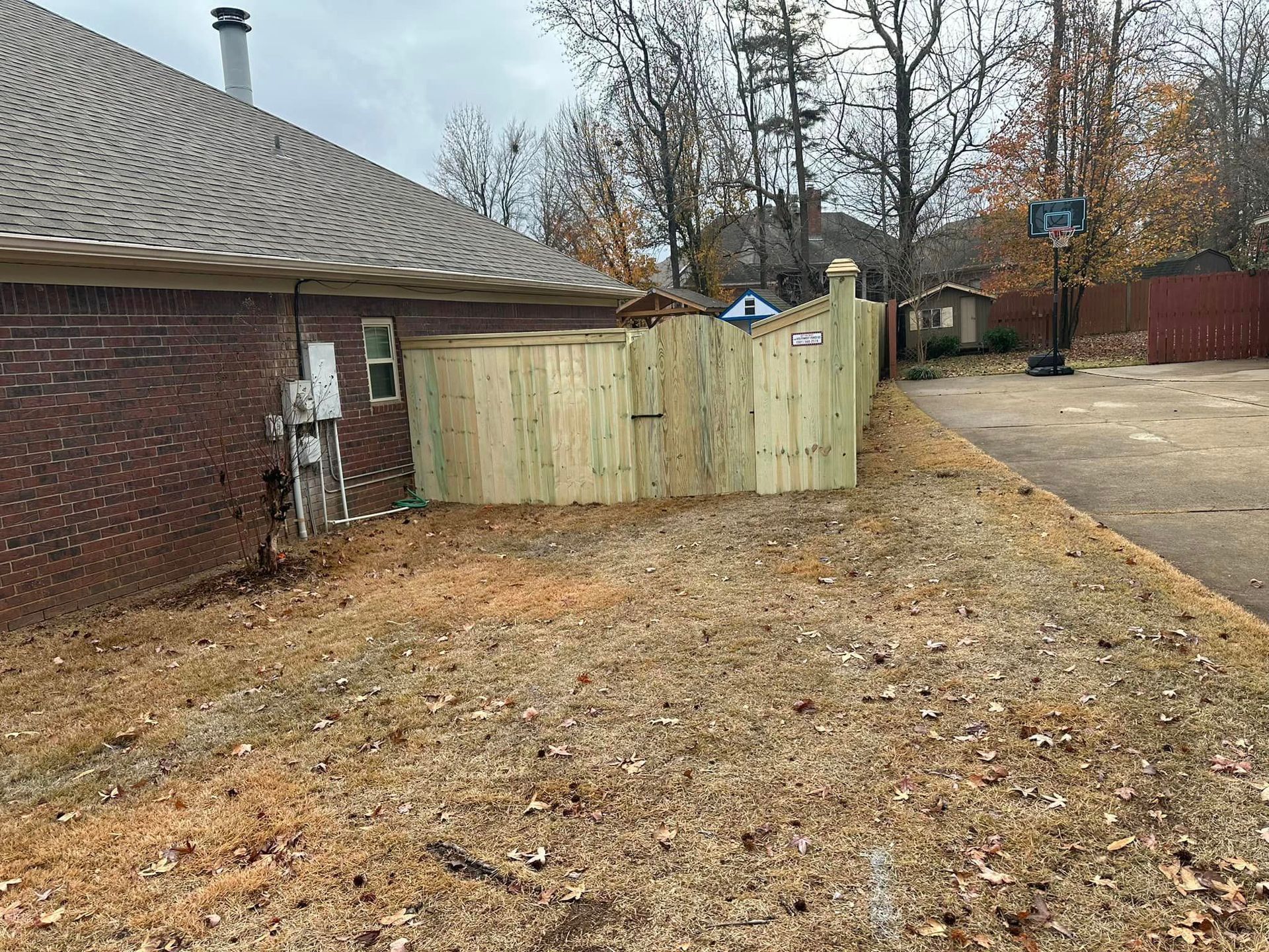 There is a wooden fence in the backyard of a house.