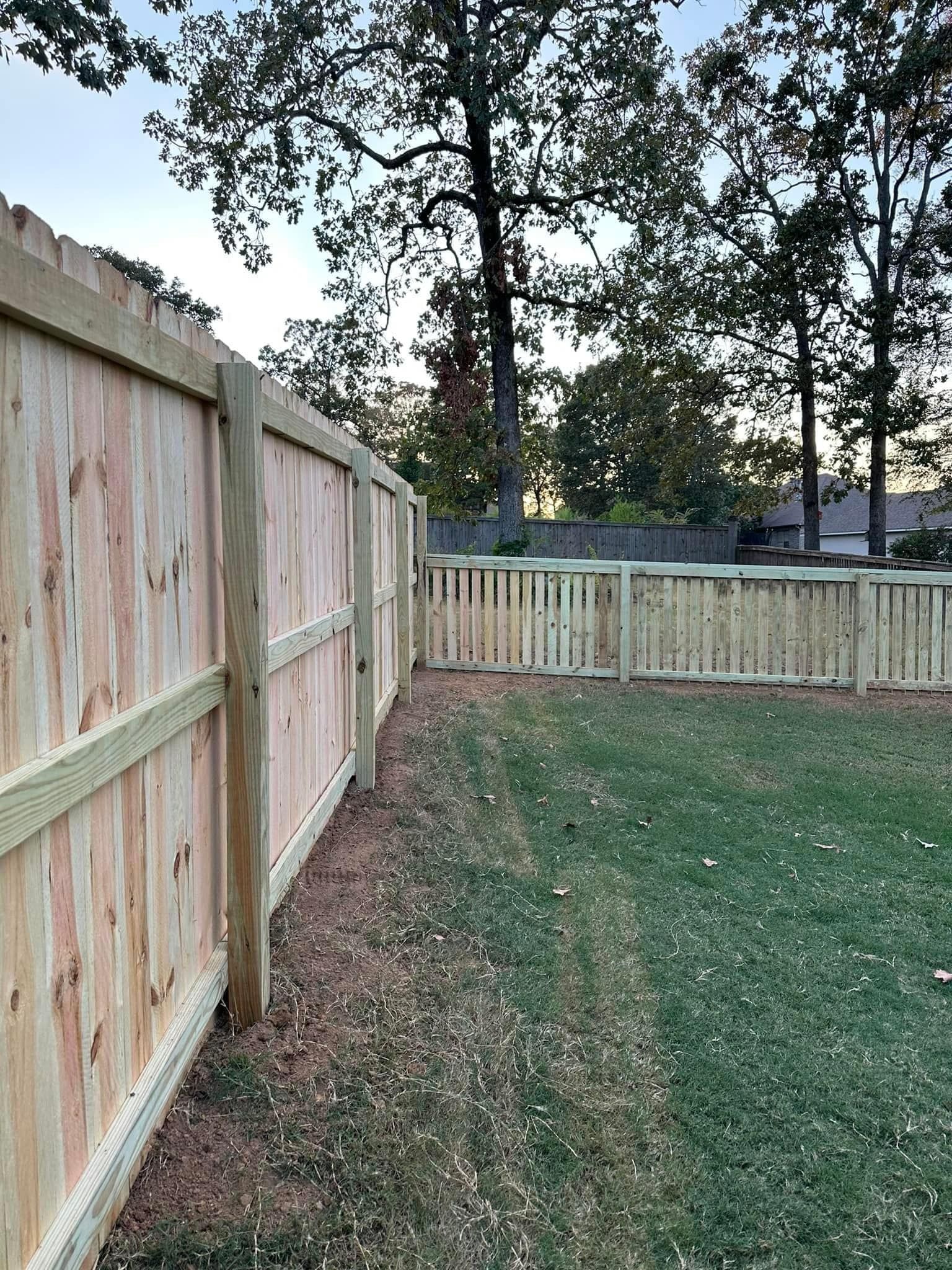 A wooden fence surrounds a lush green yard.