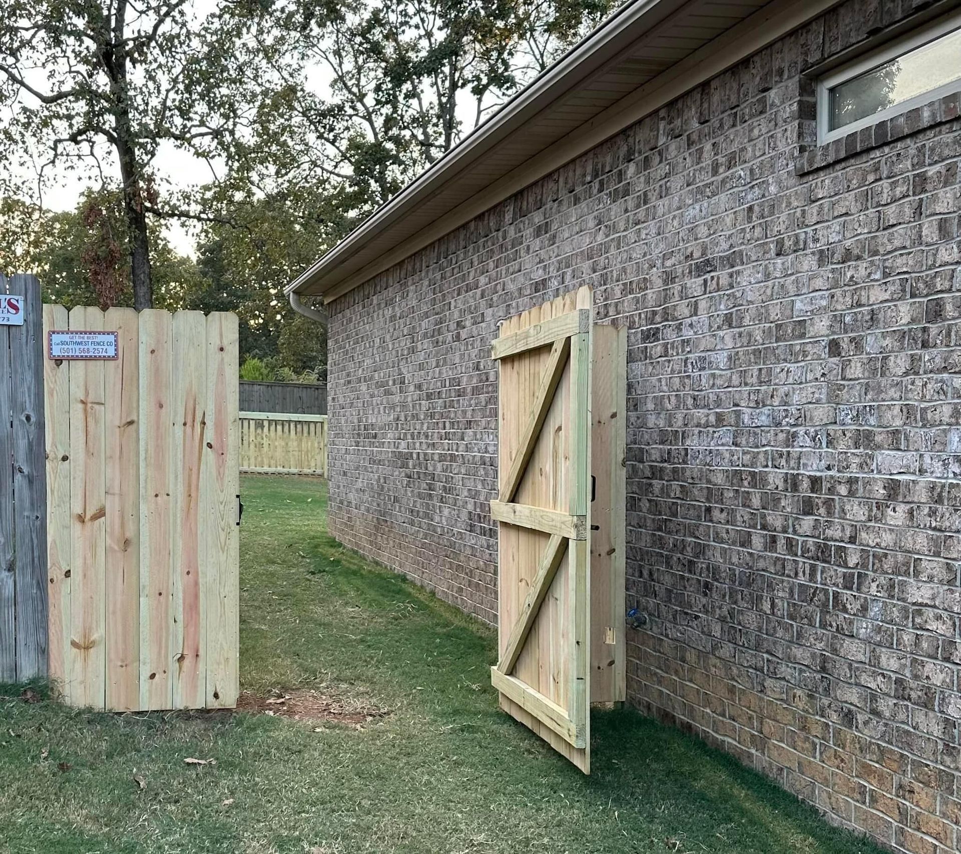 A wooden fence is next to a brick building