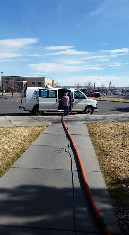 A white van is parked on the side of the road next to a sidewalk.