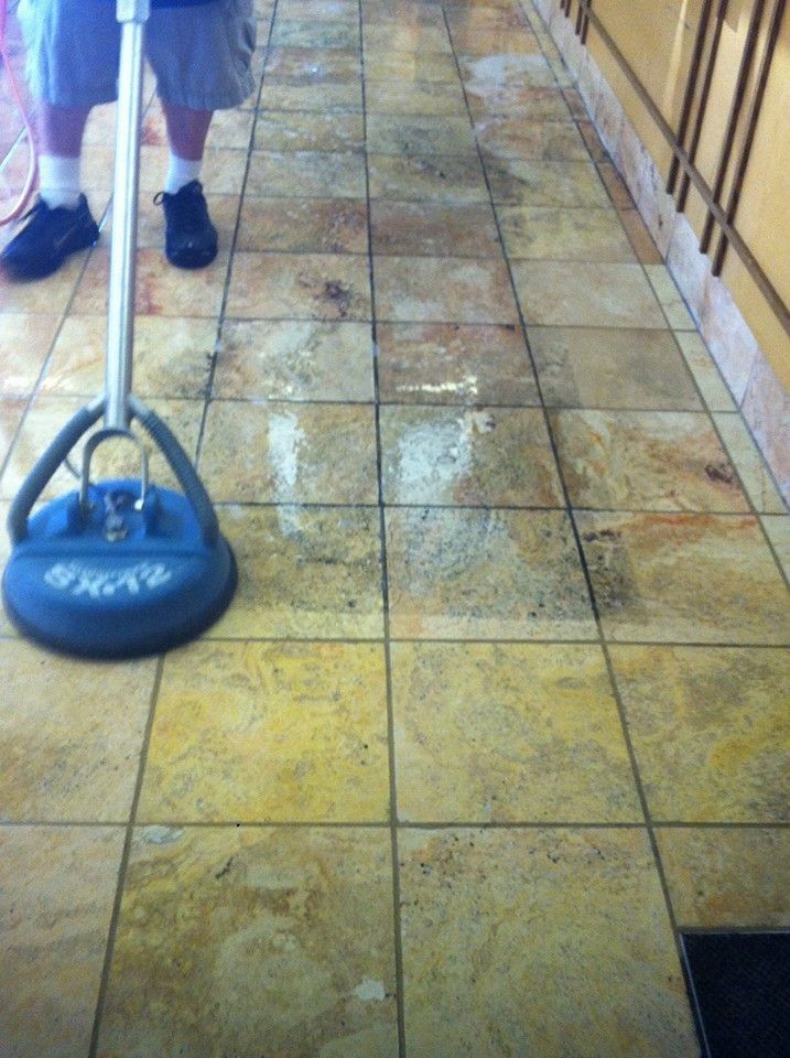 A person is cleaning a tiled floor with a metal detector.