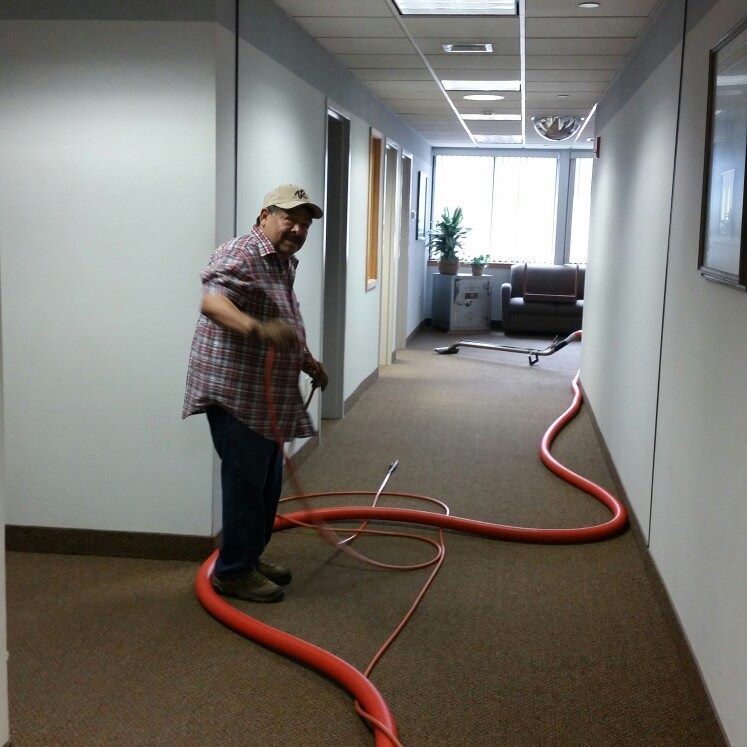 A man is standing in a hallway holding a red hose
