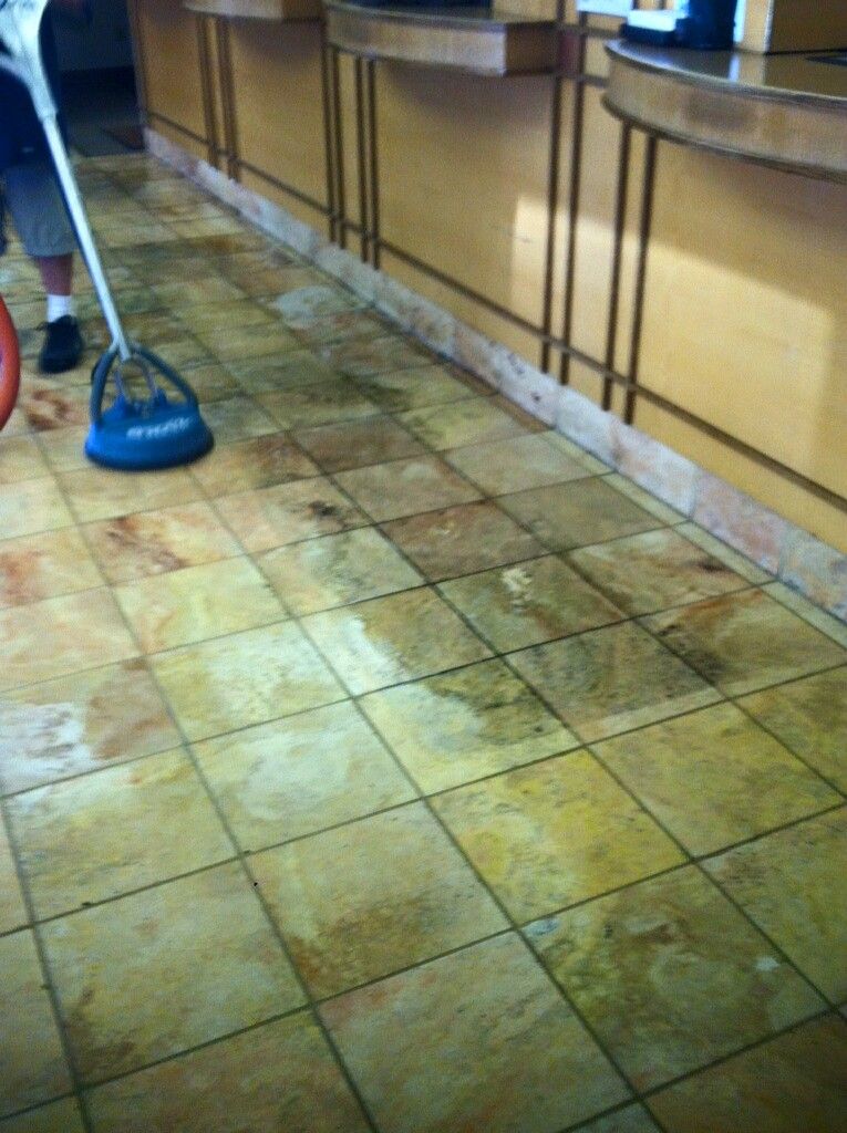 A person is cleaning a tiled floor with a mop