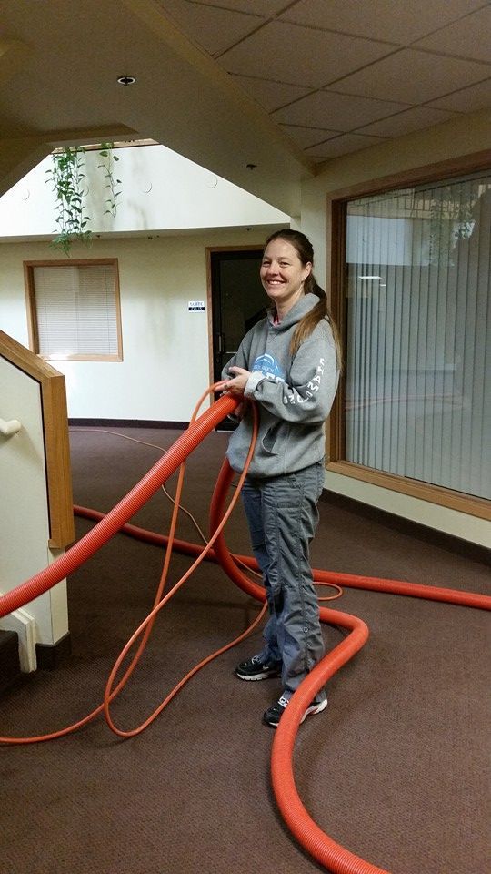 A woman is standing in a hallway holding a large red hose.