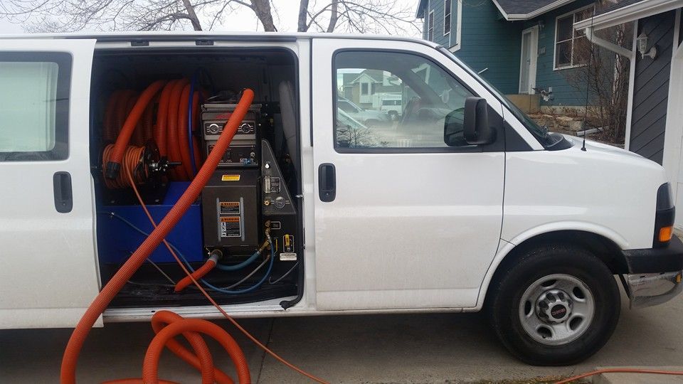 A white van is parked in front of a house with the door open