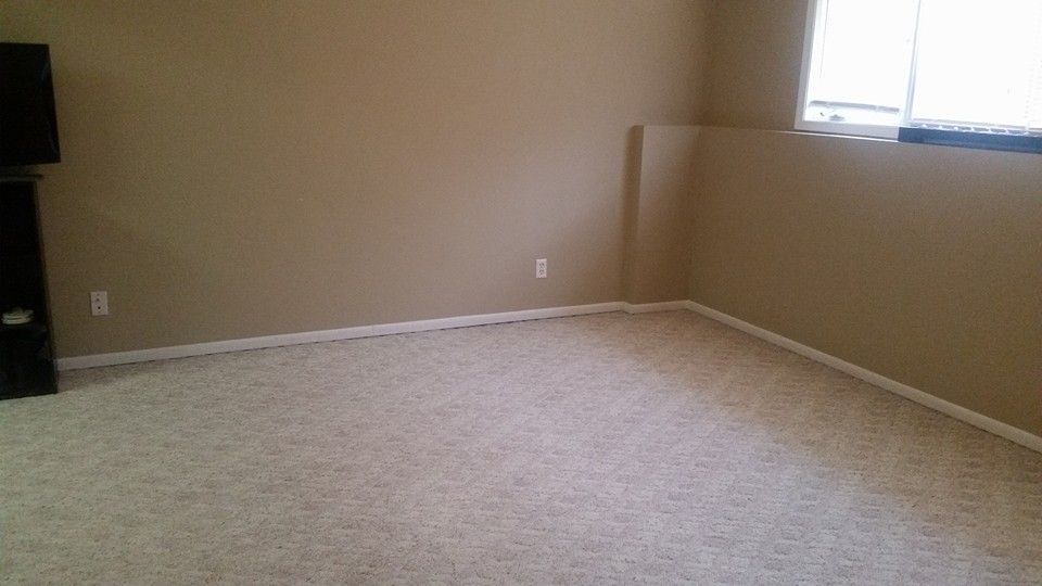 An empty room with a carpeted floor and a window.