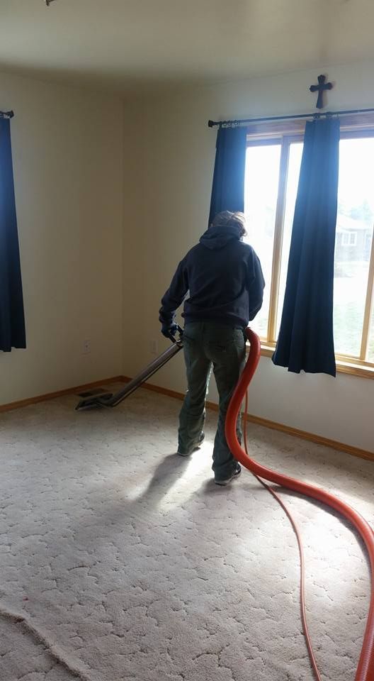 A man is using a vacuum cleaner to clean a carpet in a room.
