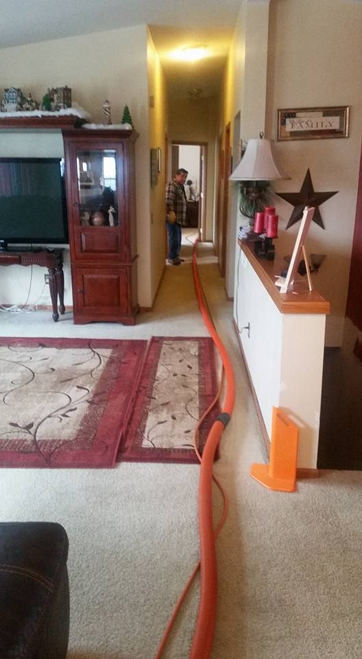 A man is standing in a living room next to a vacuum cleaner.