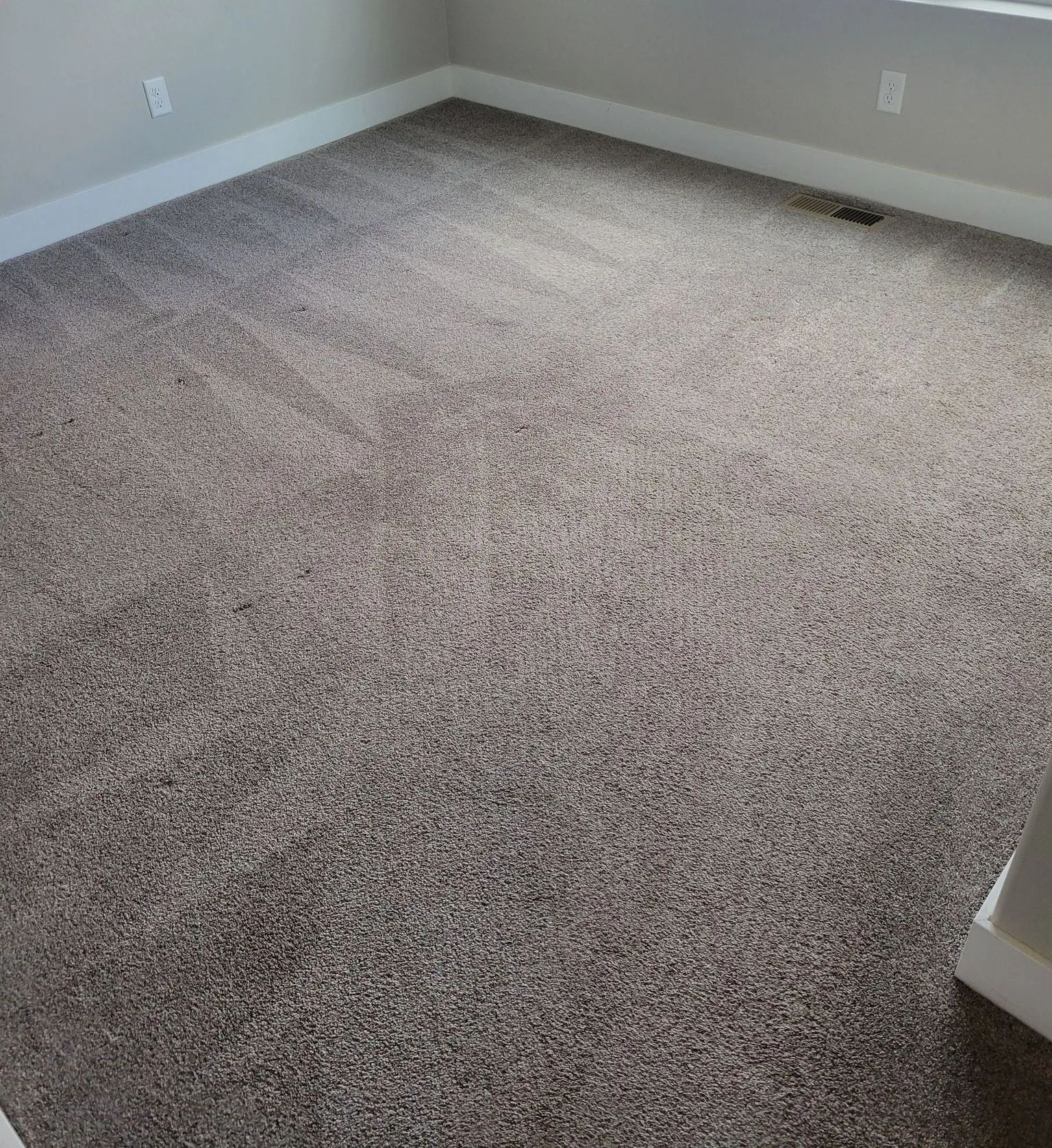 Room with neutral-colored, speckled carpet covering the floor. White baseboards and walls surround the carpet.