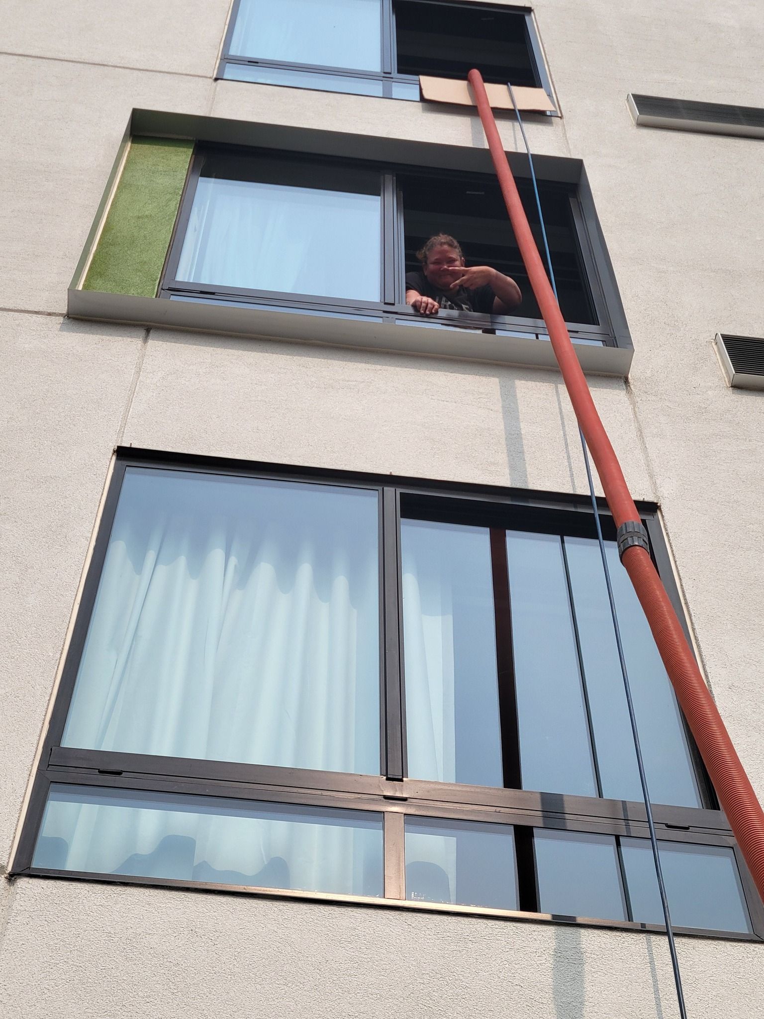 A man is looking out of a window with a hose attached to it