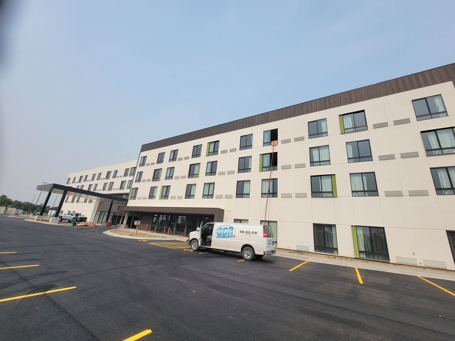 A white van is parked in front of a large building.