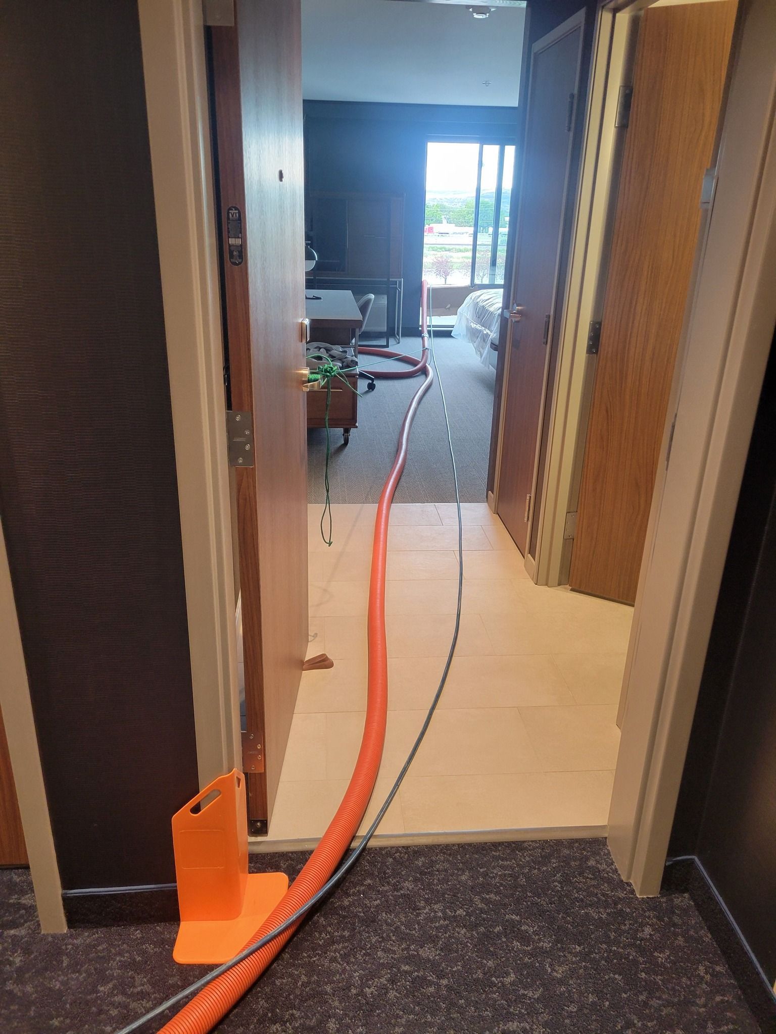 A hose is connected to a door in a hallway.