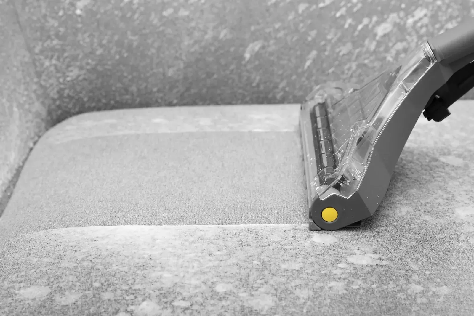 A black and white photo of a vacuum cleaner cleaning a carpet.