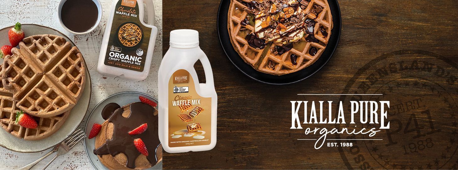 A table topped with waffles , a cake , and a bottle of syrup.