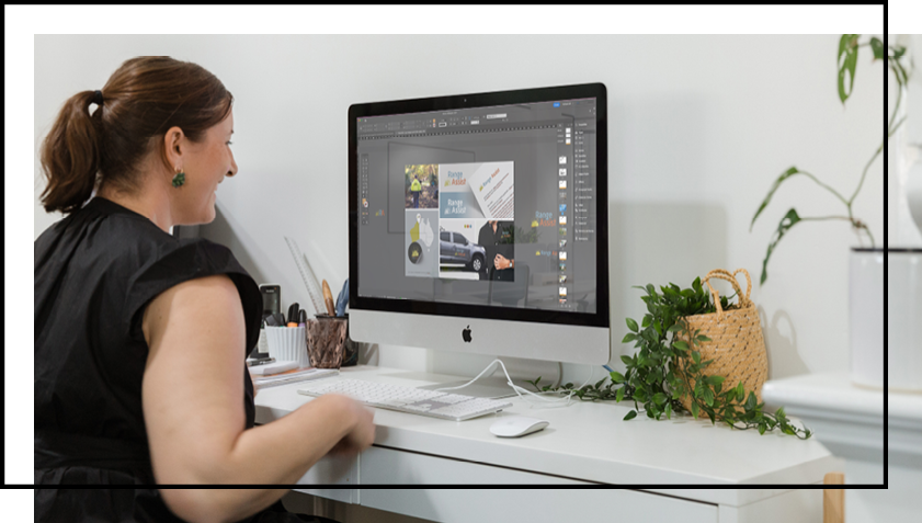 A woman is sitting at a desk looking at a computer screen.