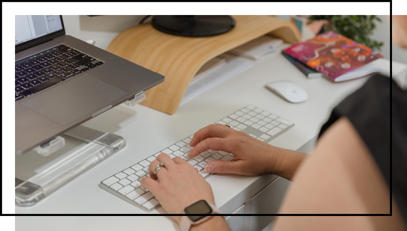 A person is typing on a keyboard in front of a laptop computer.