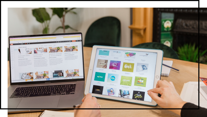 A person is using a tablet next to a laptop computer.