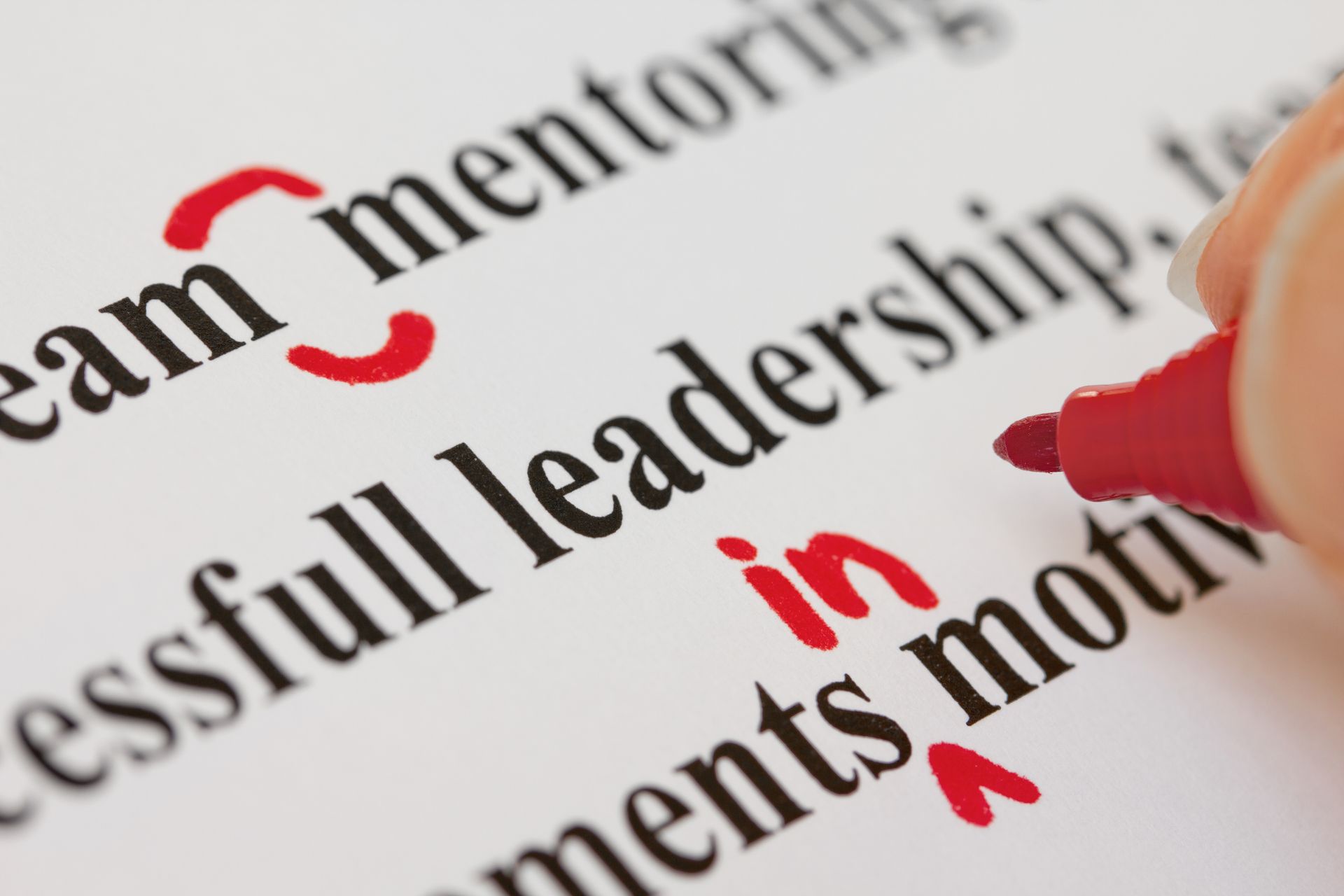 A person is highlighting the word leadership in red