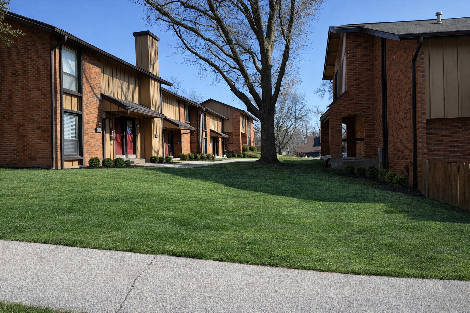 Townhouses with brick exteriors and green lawns under a blue sky.