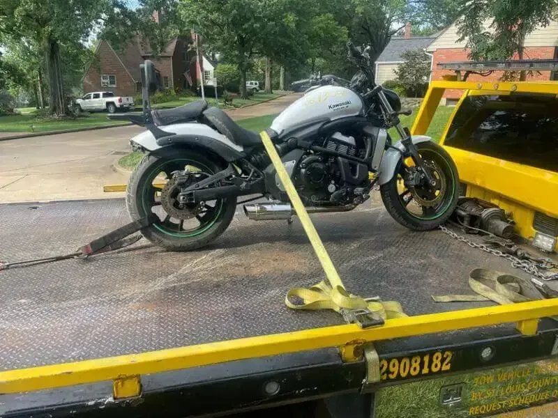 A motorcycle is sitting on top of a yellow tow truck.
