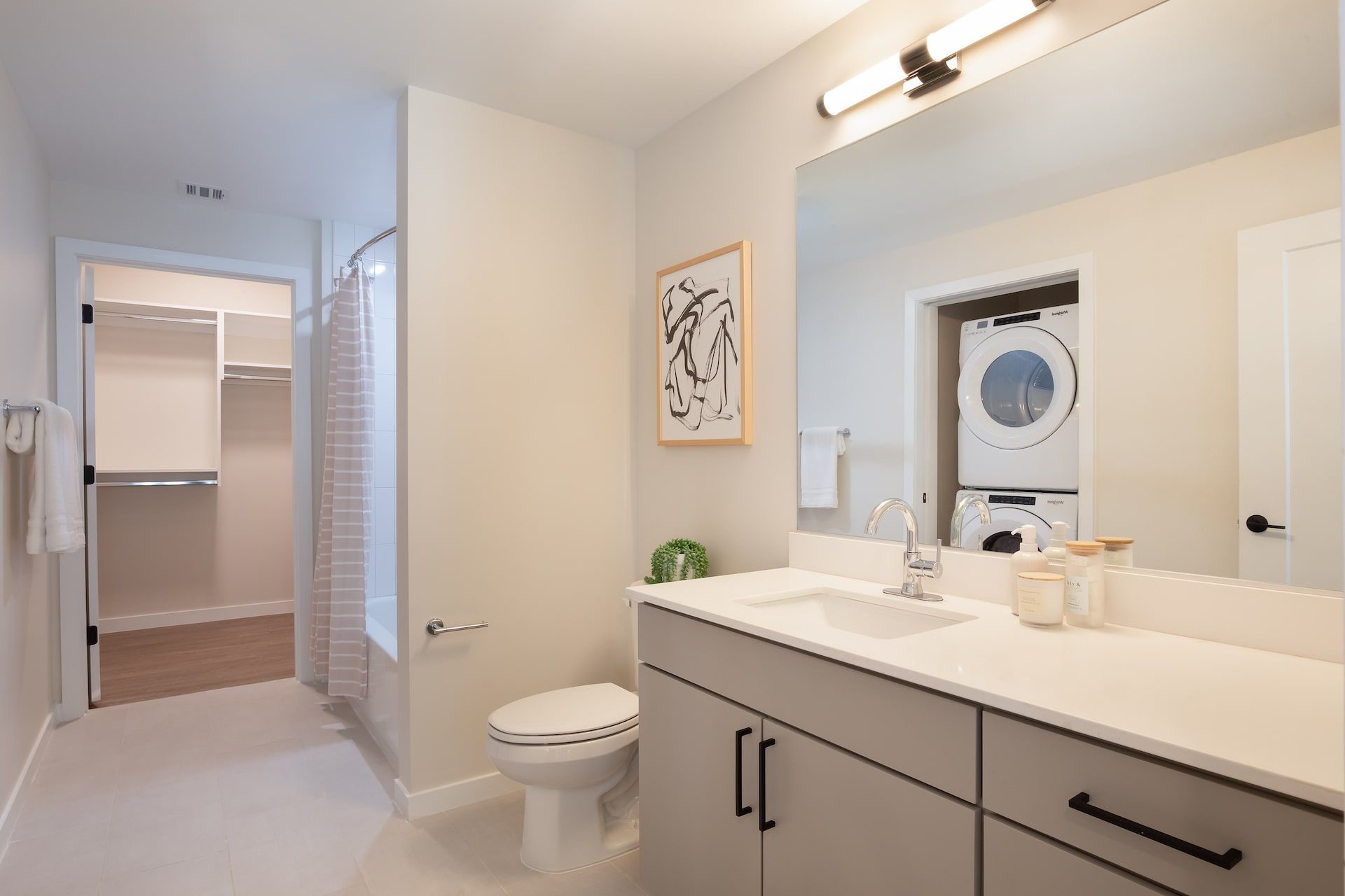 A bathroom with a toilet , sink , mirror and washer and dryer.