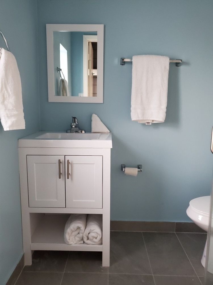 Bathroom with a white vanity, blue walls, gray tile, and a white towel hanging.