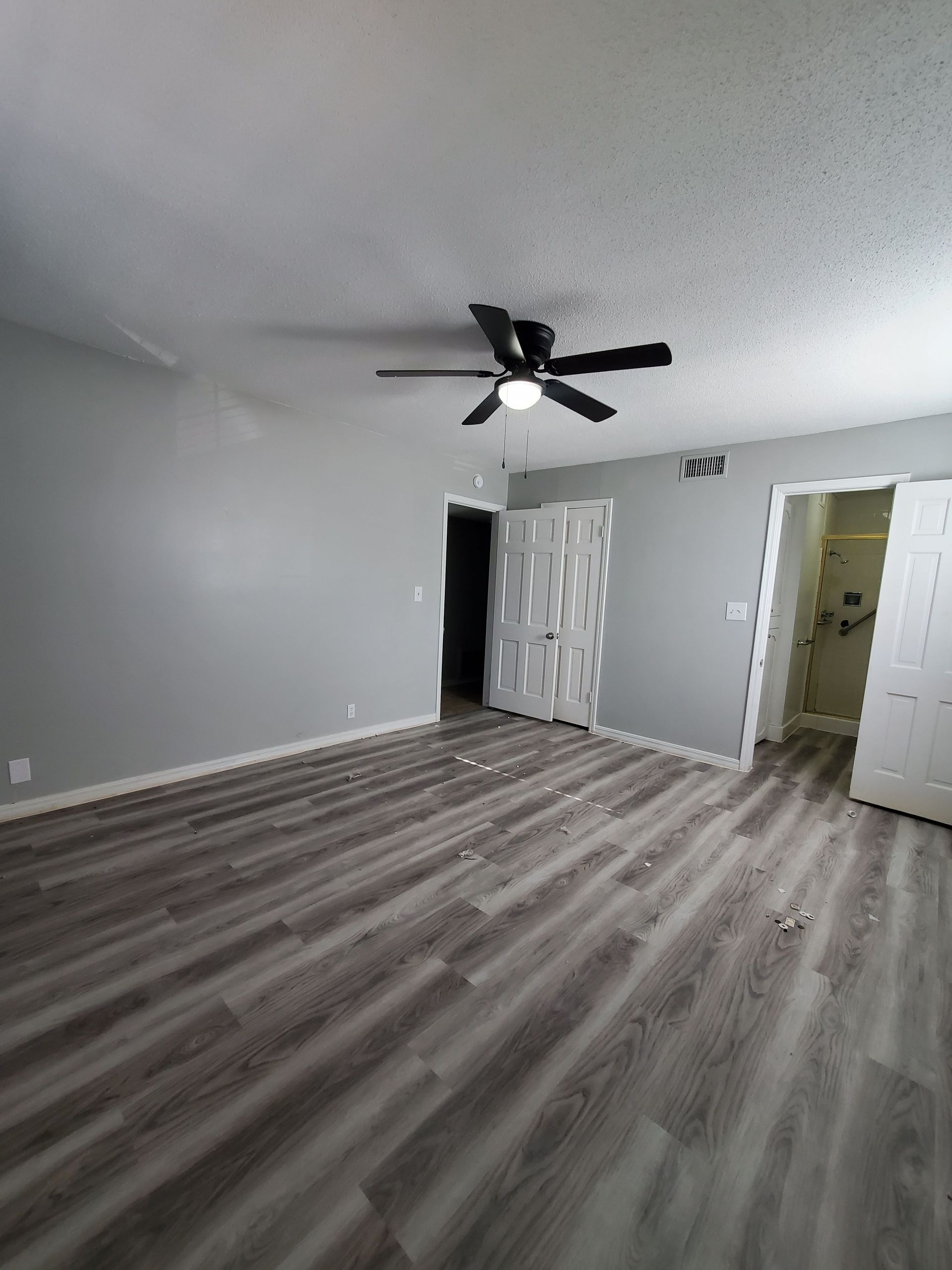 A living room with a ceiling fan and hardwood floors.
