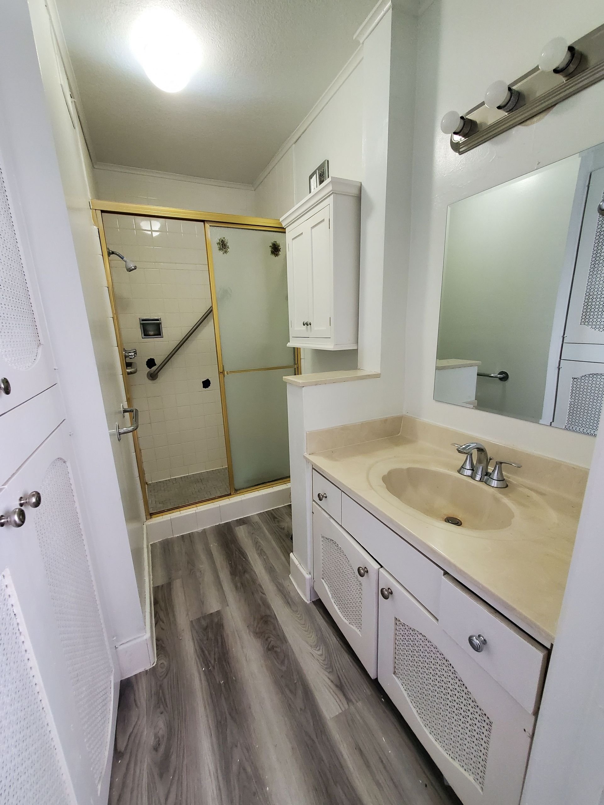 A bathroom with a sink , mirror and walk in shower.