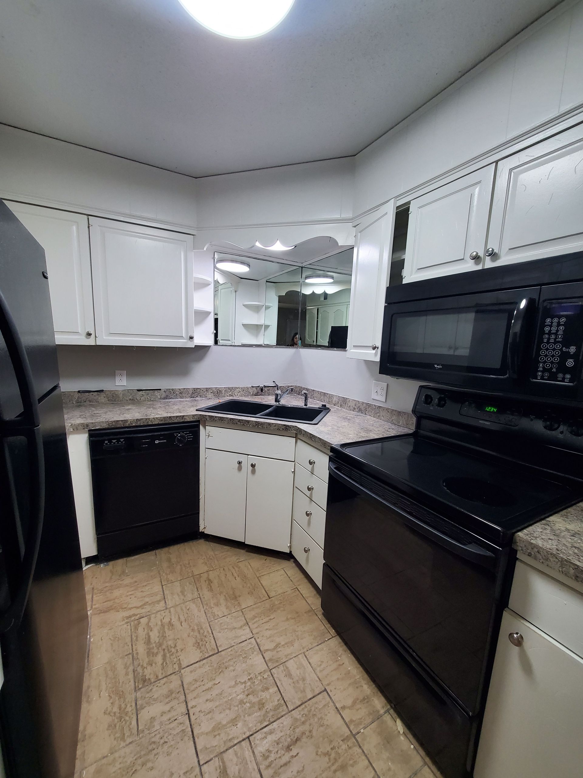 A kitchen with black appliances and white cabinets.