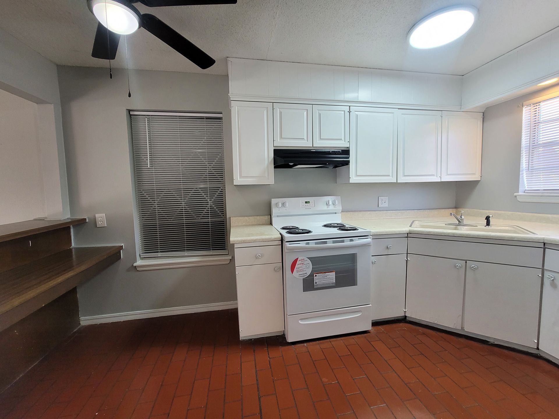 An empty kitchen with white cabinets and a stove