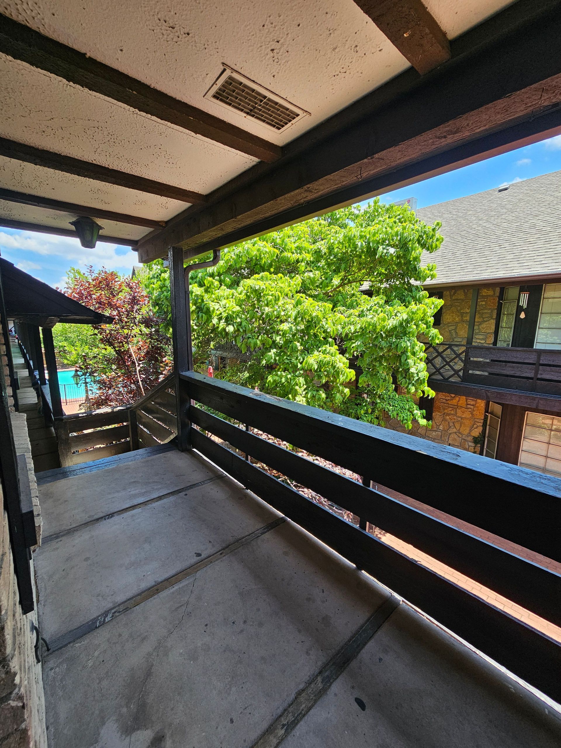 A balcony with a view of a house and trees