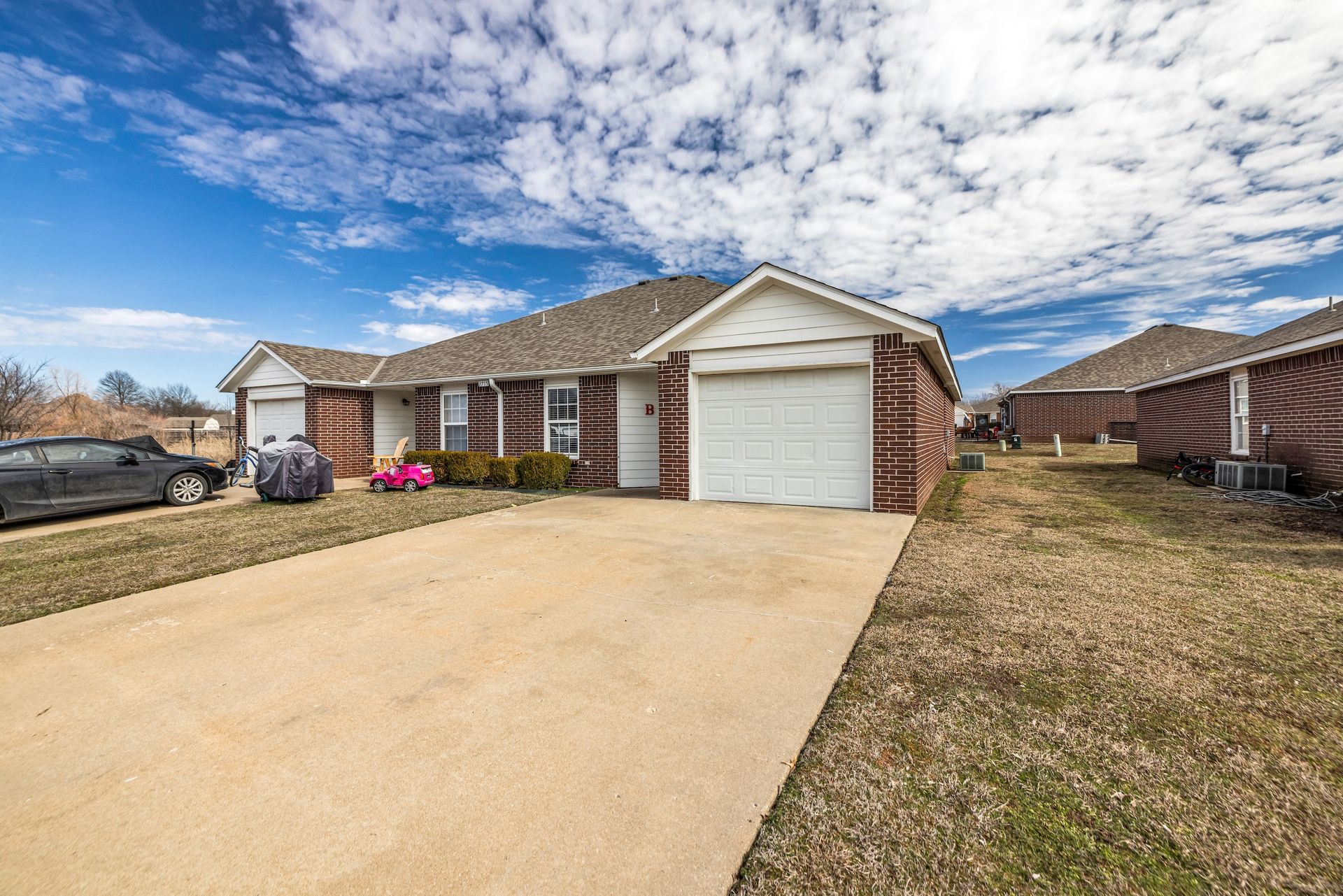 A brick house with a white garage door and a car parked in front of it.