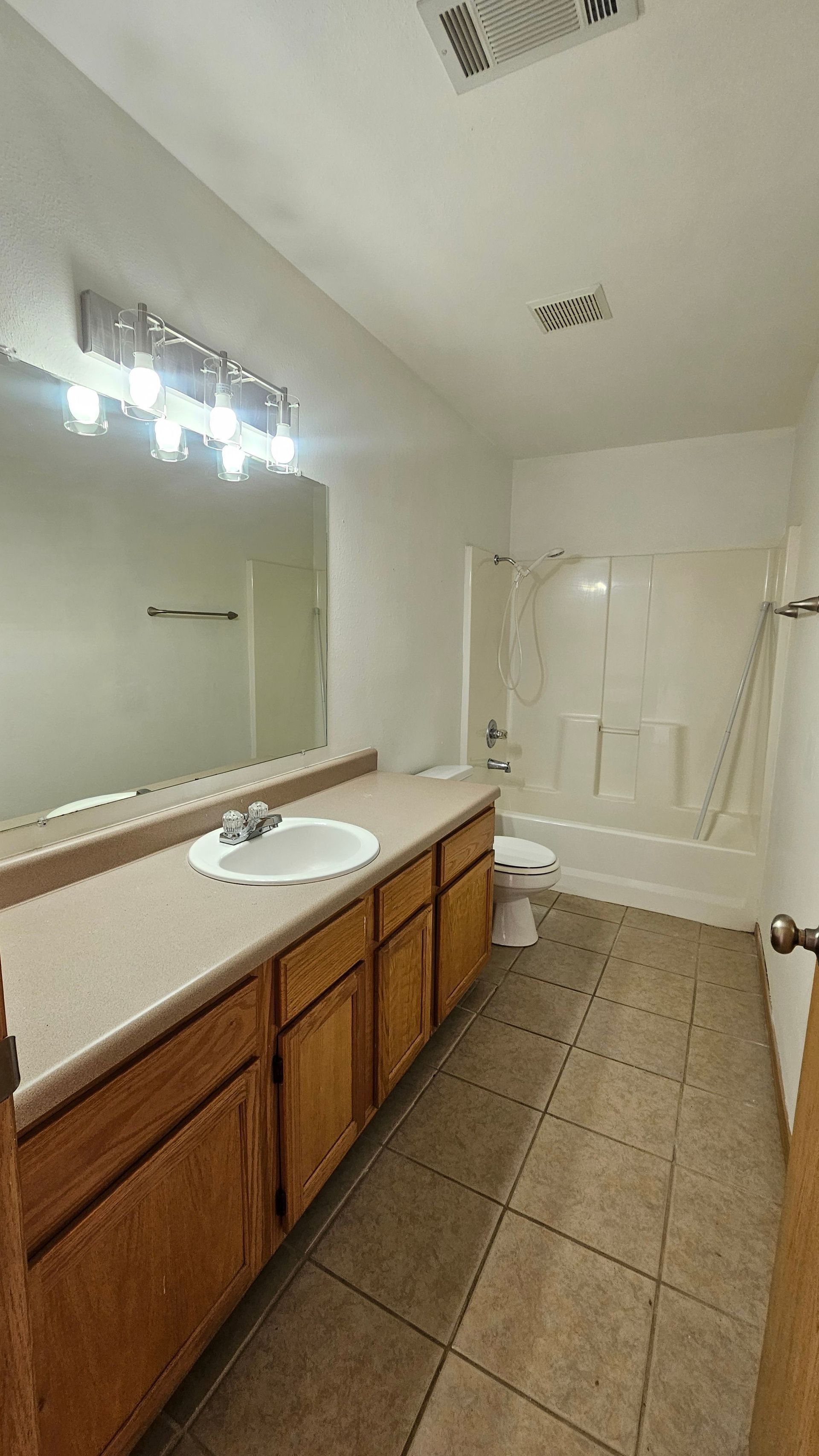 A bathroom with a sink , toilet , tub and mirror.