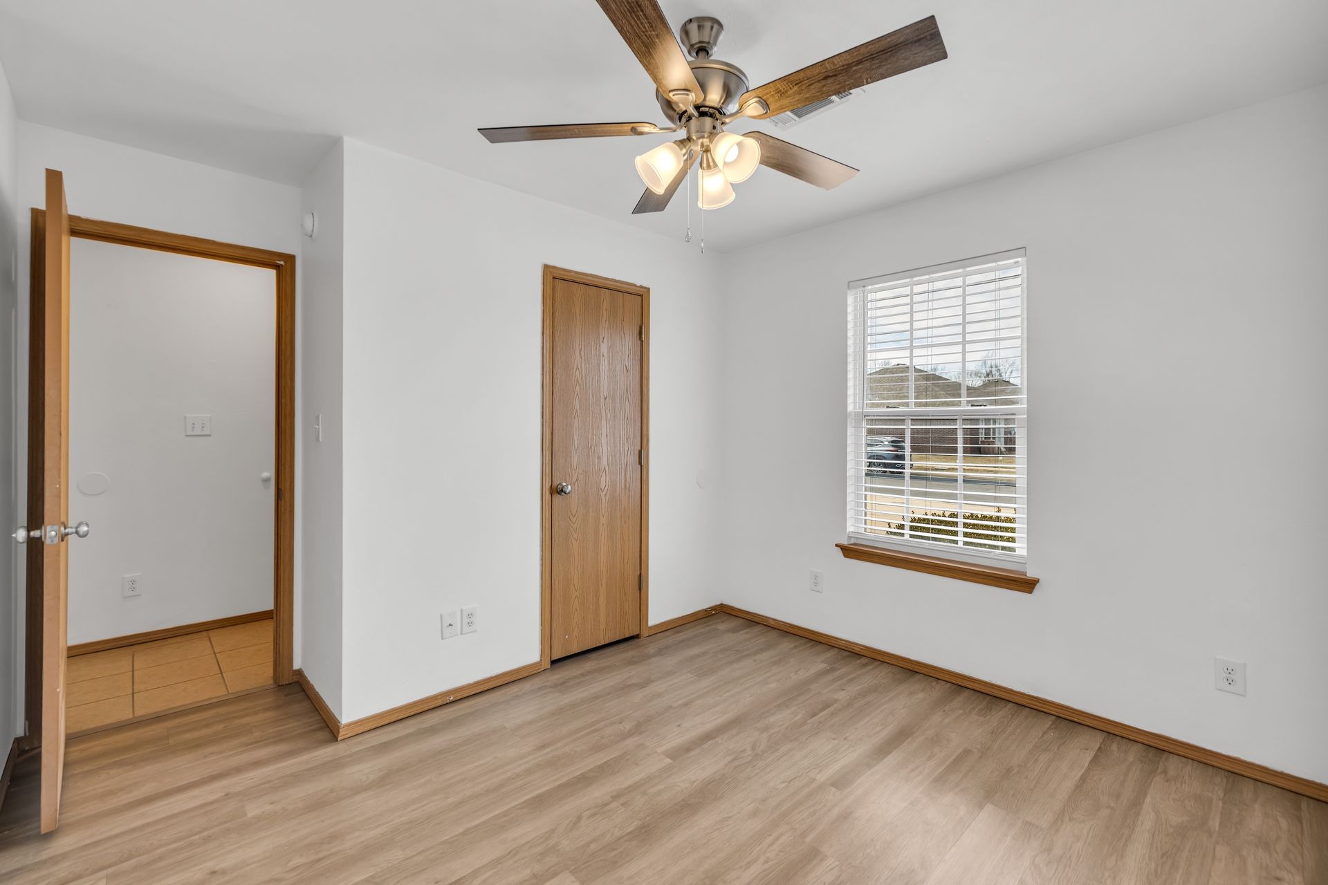 An empty bedroom with a ceiling fan and a window.